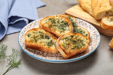 Plate of toasts with garlic and dill on grunge background