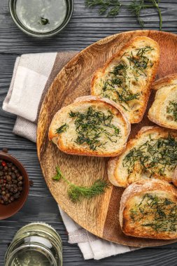 Plate of toasts with garlic and dill on dark wooden background, closeup