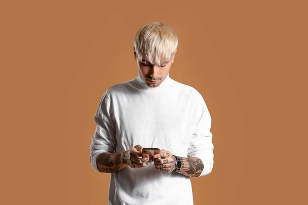 Young Tattooed Man White Sweater Using Mobile Phone Brown Background — Stockfoto