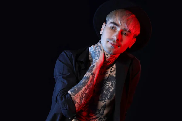 Young tattooed man on black background