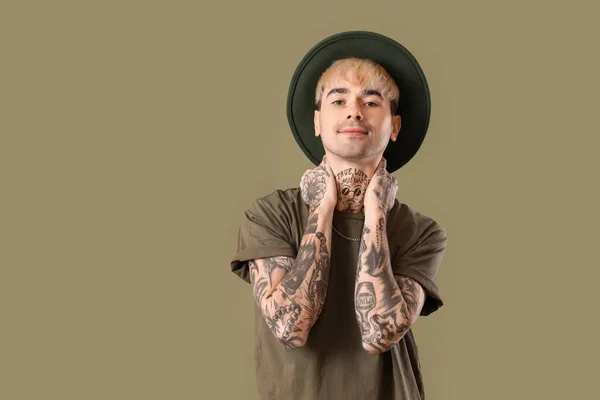 Young tattooed man in hat on green background