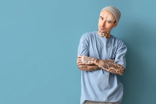 Young tattooed man on blue background