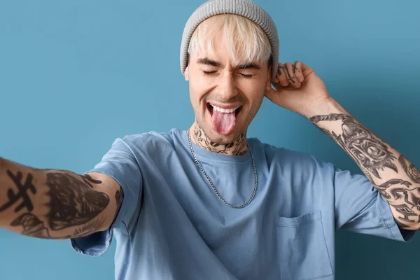 Young Tattooed Man Showing Tongue Blue Background — Stockfoto