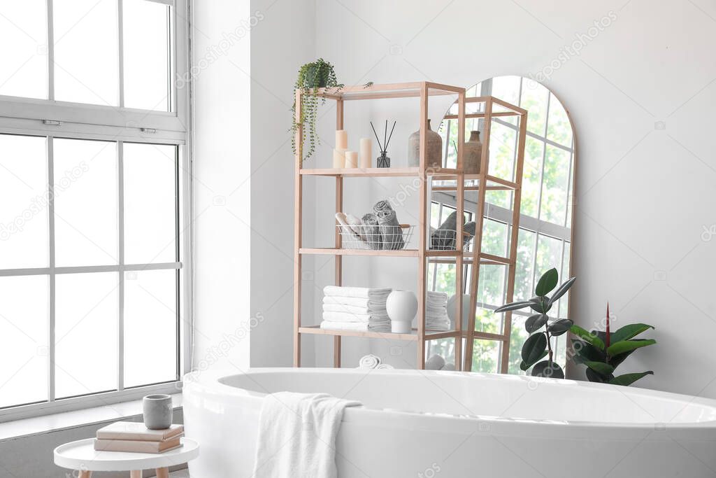 Interior of light bathroom with wooden shelving unit and mirror