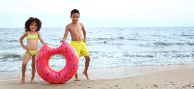 African-American children with inflatable ring on sea beach at resort