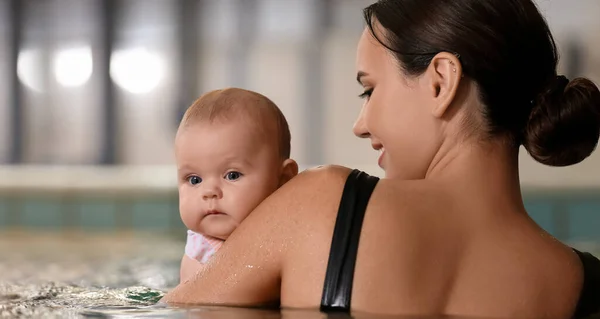 Young swimming coach with little baby in pool
