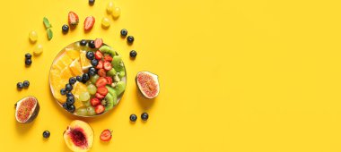 Composition with tasty fruit salad on yellow background with space for text