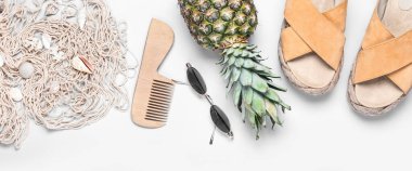 Stylish beach accessories with pineapple on light background