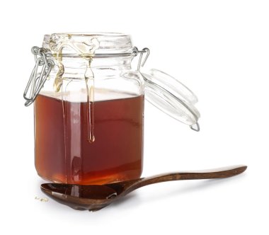 Glass jar and spoon with tasty maple syrup on white background