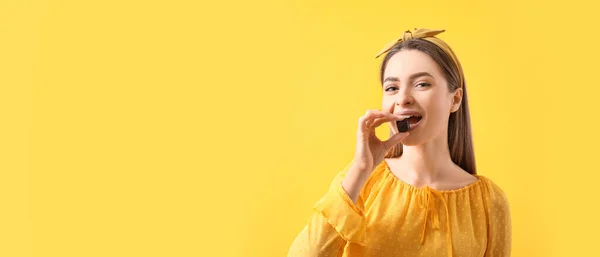 Beautiful Young Woman Eating Delicious Chocolate Candy Yellow Background Space — 스톡 사진