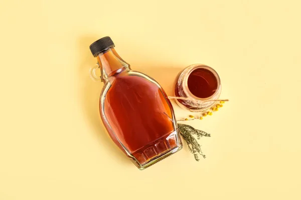 Bottles of tasty maple syrup on color background