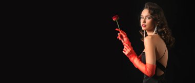 Fashionable young woman holding beautiful red rose on dark background with space for text