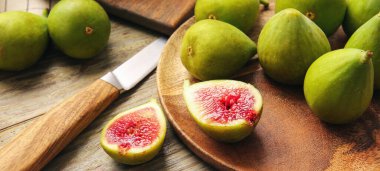 Plate with fresh green figs and knife on wooden background, closeup