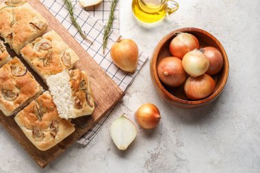 Wooden board with tasty Italian focaccia and bowl of onion on light background