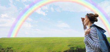 Female tourist looking at beautiful rainbow in countryside