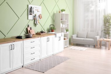 Beyaz tezgahlı, tahta tahtalı ve raf üniteli şık bir mutfak.