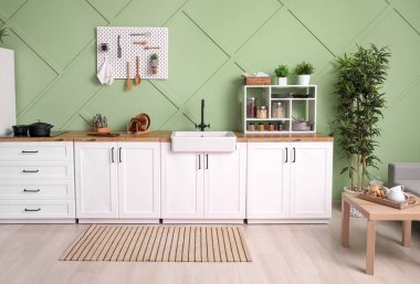 Interior of stylish kitchen with white counters, pegboard and shelving units