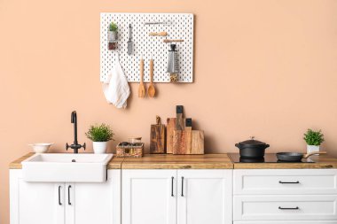 kitchen counters with sink and utensils near beige wall