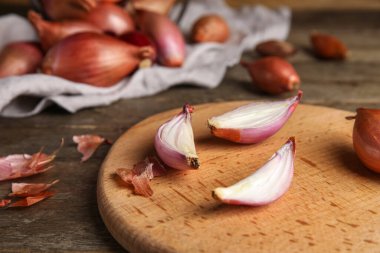 Board with fresh onion on wooden table, closeup