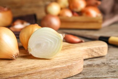 Board with onion on wooden background, closeup
