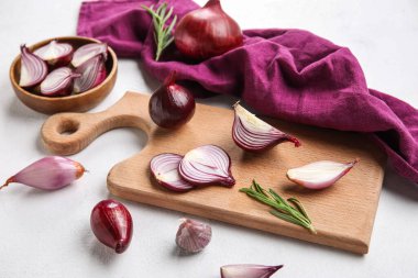 Wooden board with cut red onion on light background