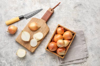 Composition with wooden board and box of onion on grunge background
