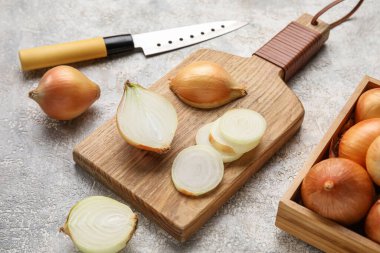 Wooden board with fresh onion on grunge background