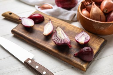 Board with cut red onion on light wooden background, closeup