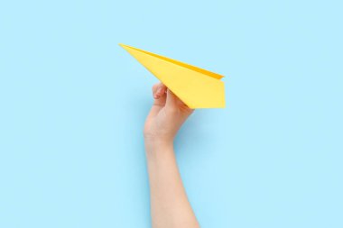 Woman with yellow paper plane on blue background