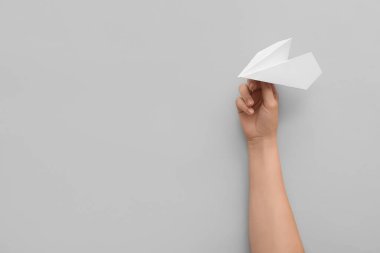 Woman with white paper plane on light background