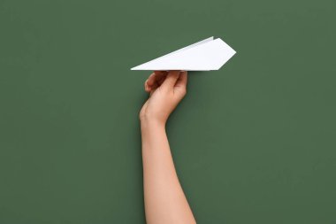 Woman with white paper plane on green background