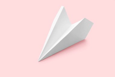 White paper plane on pink background