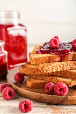 Plate with tasty toasts and raspberry jam on white wooden background, closeup