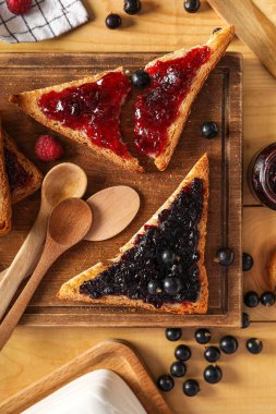 Tasty toasts with raspberry and black currant jam on table, closeup
