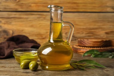 Decanter and bowl with fresh olive oil on wooden background