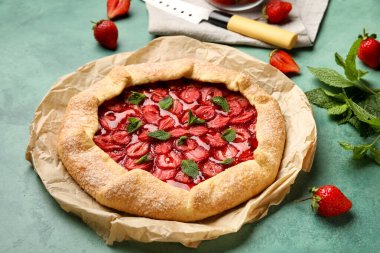 Tasty strawberry galette on green background