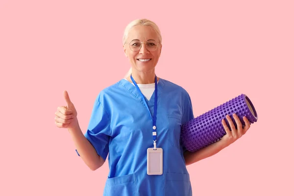 Mature Physiotherapist Foam Roller Showing Thumb Pink Background — Stockfoto
