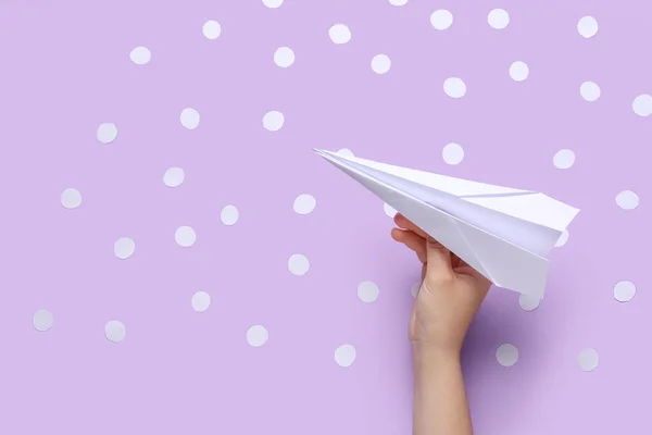 Woman with paper plane and dots on lilac background