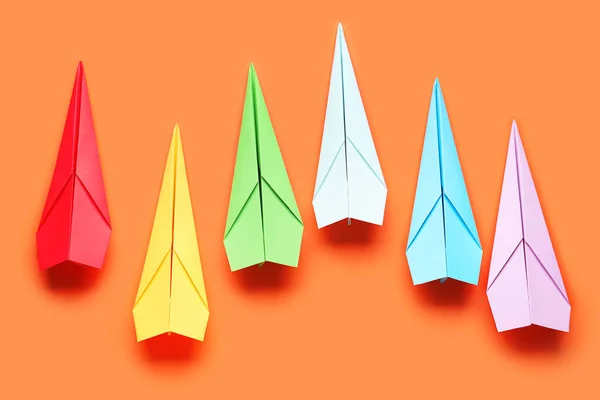 Colorful paper planes on orange background