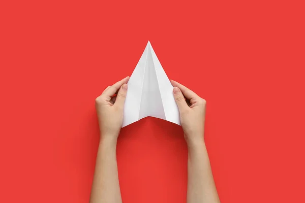 Woman with white paper plane on red background