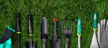 Different gardening tools on green grass outdoors, top view