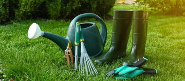 Gardening tools and gumboots on green grass outdoors