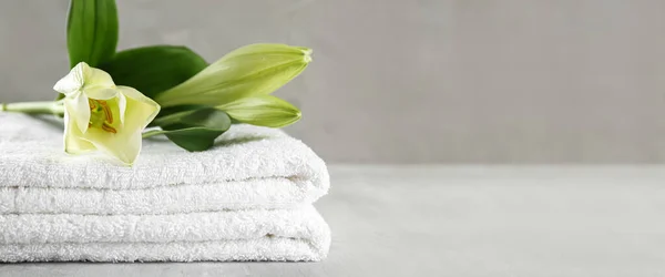 Soft towels and flower on grey table. Banner for design