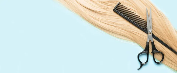 Blonde hair, comb and scissors on light blue background with space for text