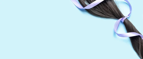 Dark hair and ribbon on light blue background with space for text