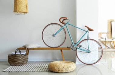 Modern bicycle on wooden bench near light wall in bedroom