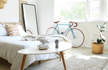 Interior of light bedroom with bicycle and mirror