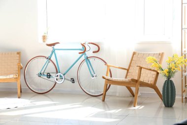 Modern bicycle and armchairs near window in light room