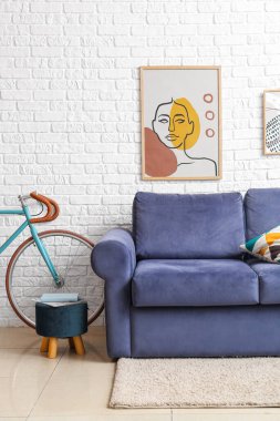 Bicycle, blue sofa and pouf near white brick wall