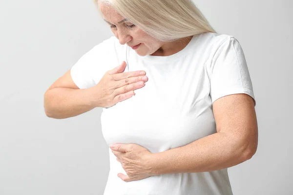 Mature Woman Suffering Breast Pain Light Background — Stockfoto
